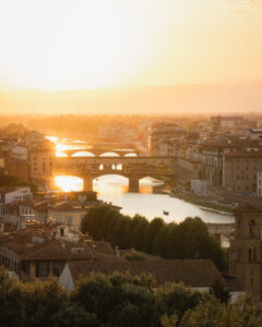 Fotografía urbana al atardecer con río, puentes y luz cálida reflejada