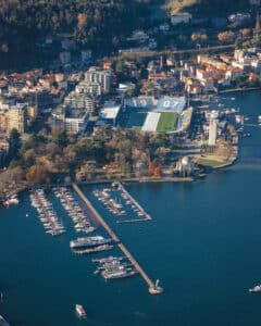 Fotografía aérea urbana con puerto, lago y trama de ciudad integrada, con estadio de futbol